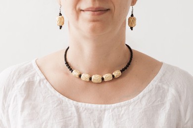 a girl with a necklace and earrings made of a black beads and straw. trendy sustainable fashion accessories. small depth of field 