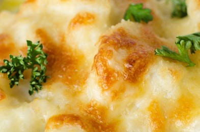 close up (macro) of baked cauliflower cheese with scattered