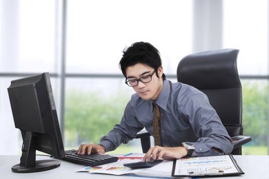 young businessperson working with computer, calculator, and documents in the office near the window