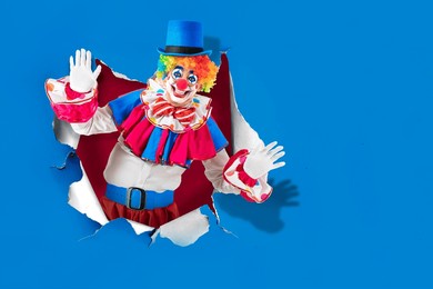 funny clown in the circus  looking through the ripped paper hole, man entertainer as joker, with clown whiteface makeup. trickster, jester, pantomime, mime, and a professional actor at events