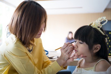 professional makeup artist working with cute asian child