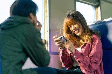 happy young asian woman enjoy and fun outdoor lifestyle road trip by railroad transportation on summer holiday vacation. attractive girl using digital camera taking picture during travel on train