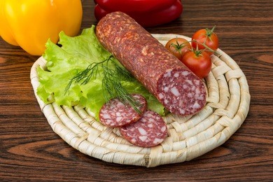 sliced salami with salad leaves on the wood background