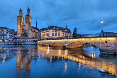 munsterbrucke and grossmunster church reflecting in river limmat, zurich, switzerland