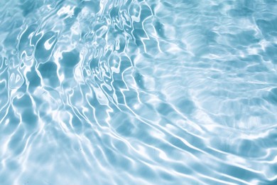 light blue water with ripples on the surface. defocus blurred transparent clear calm water surface texture with splashes and bubbles. water waves with shining pattern texture background.