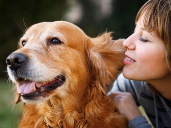 girl whispering in her dog's ear in the park