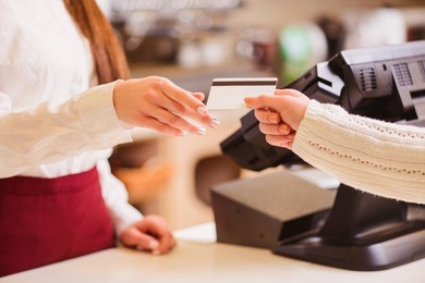 thanks for your purchase. cropped image of a customer paying to shop assistant by a credit card at the cash desk