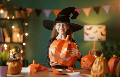 cute little child girl with polygonal paper pumpkin. happy family preparing for halloween. 