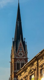 majestic church herz jesu kirche at sunrise in graz, styria, austria. landmark against clear blue sky. intricate architectural details, including pointed spire, ornate windows, clock face