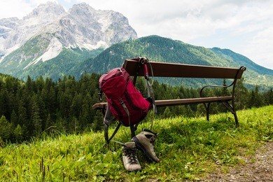 hanging backpack and hiking shoes with mountains in the background. south tyrol.