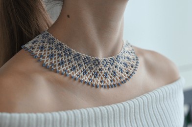 close-up of a beaded necklace sylianka on a woman’s neck, featuring a delicate net pattern with blue and white beads.