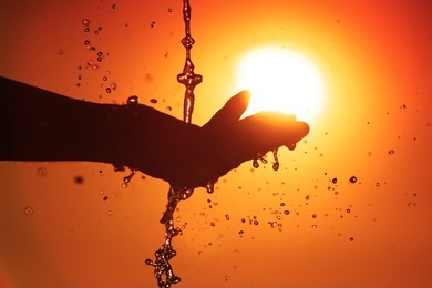 abstract spout of water to the hand and beautiful sunset