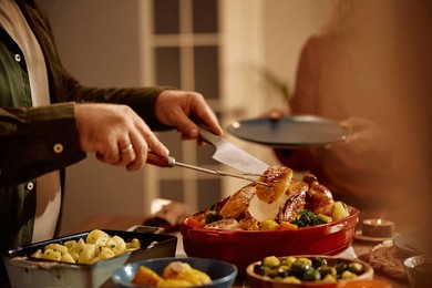 cloe up of man carving roast turkey during thanksgiving dinner in dining room. 