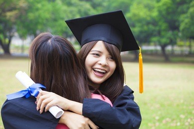 young female graduate hugging her friend at graduation ceremony