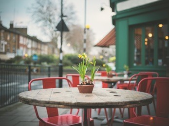 a table decorated with lillys outside a cafe in the street on a winter's day