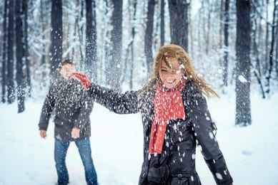 winter couple having fun playing snowball fight