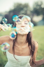 beautiful young woman with white dress blowing bubble in the city