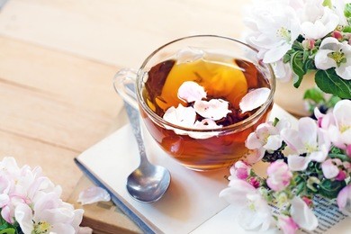 books, flowers and cup of tea on wooden table.