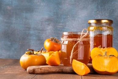 persimmon jam. sweet autumn homemade jam or marmalade canning preserves in a jar, with whole and cut persimmon c in the background