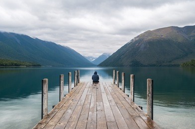 men sitting on a pier at lake nelson in new zealand