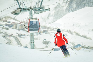 male skier skiing downhill fast pass cabin lift in snowy conditions to gondola with mountains background. gudauri winter holiday resort. georgia travel destination. caucasus