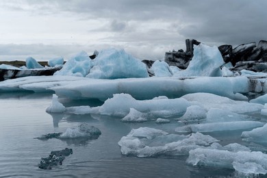 iceland's blue ice floats on water next to a glacier