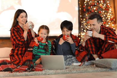 happy family with cocoa watching christmas movie on laptop at home