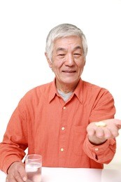 senior japanese man takes a supplement