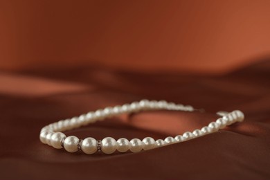 beautiful pearl necklace on brown silk, closeup