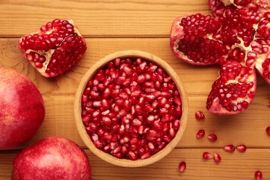 open pomegranates, and pomegranate seeds on wooden background. top view