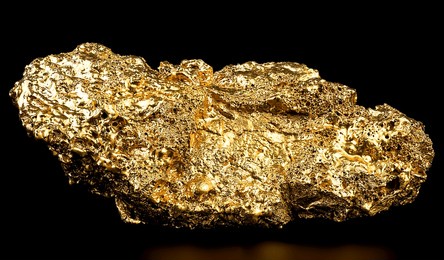 pure gold from the mine on black background. closeup of gold nugget. finance and business concept.