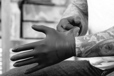 closeup of the hands of a tattoo artist putting on the latex gloves before a tattoo session at the tattoo shop - focus on the right forefinger