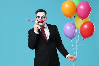 young man as clown businessman with party whistle and balloons on blue background
