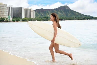 portrait of surfer woman running surfing with surfboard having fun on waikiki beach, oahu, hawaii. female bikini girl on surfboard smiling happy living healthy lifestyle on hawaiian beach.