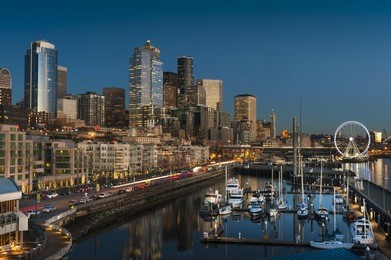 seattle waterfront at sunset. the seattle, washington waterfront and skyline at sunset with a marina and ferris wheel. the port of seattle can be seen in the background.
