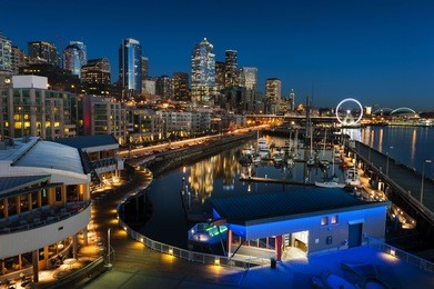 seattle waterfront at sunset. the seattle, washington waterfront and skyline at sunset with a marina and ferris wheel. the port of seattle can be seen in the background.