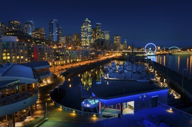 seattle waterfront at sunset. the seattle, washington waterfront and skyline at sunset with a marina and ferris wheel. the port of seattle can be seen in the background.