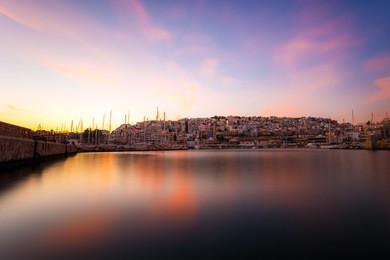 typical colorful evening scenery in the mikrolimano marina in athens in the afternoon, with clouds over the city lights and many restaurants on the seafront in greece long exposure photography