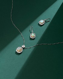 elegant opal jewelry set featuring a necklace and earrings, beautifully styled on a green background with soft shadows