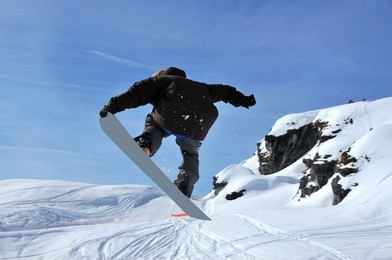 a snowboarder performing a jump and touching his board