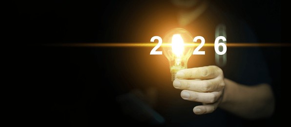 happy new year 2026. a man holds an illuminated light bulb with the changing year to 2026, to start or begin the year with new idea.