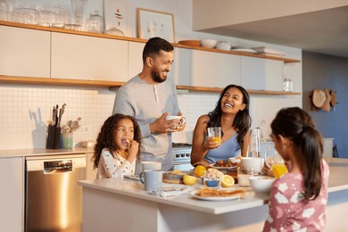 hispanic family enjoy a cheerful breakfast together in modern kitchen. mixed race family with two daughters sharing a joyful morning meal around the kitchen island. multiethnic family having breakfast