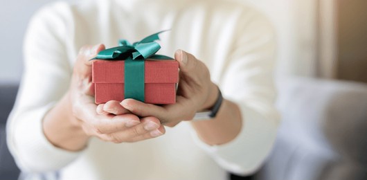 close up young man hand hold red gift box with green ribbon to send to someone special in festive season for people lifestyle concept