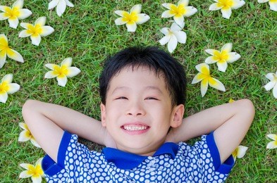 asian boy lying on grass field with flower