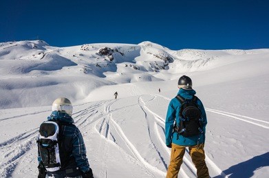 snowboarders waiting for their friend during free-ride off-piste run on snowy mountain 