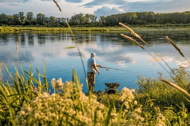man fisherman with fishing rod fishing in river fishing lake waterscape