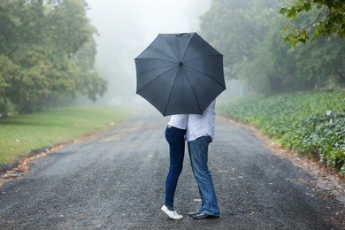 couple kissing behind the umbrella in the mist