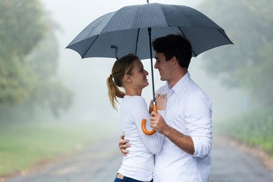 lovely young woman with boyfriend under an umbrella in the rain