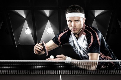 portrait of young man playing tennis on black background with lights