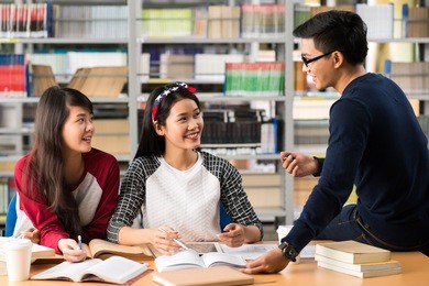 asian college students talking while doing homework in the library
